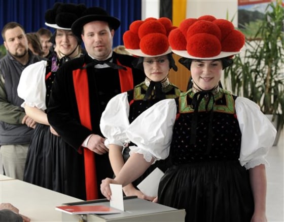 Citizens of Gutach, from right: Tanja Lauble, Christine Haas, Mike Lauble und Melanie Haas in traditional Black Forest clothes, line up to cast their ballots in Gutach, southern Germany on Sunday. Eight million Germans are voting in a closely watched state election that could see Chancellor Angela Merkel's conservative party lose power in southern Baden-Wuerttemberg for the first time in almost six decades. Recent polls suggest Merkel's Christian Democrats are poised to lose Sunday's ballot by a narrow margin, with the opposition Social Democrats and Greens scoring about 24 percent each and forming a coalition government in the state.